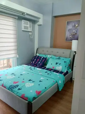 a bedroom with a bed with a blue comforter at Sweet Condo in Manila