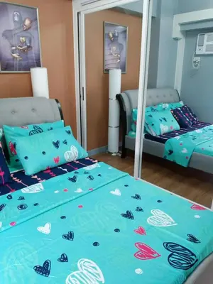 a bedroom with two beds and a mirror at Sweet Condo in Manila