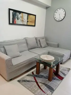 a living room with a couch and a table and a clock at Sweet Condo in Manila