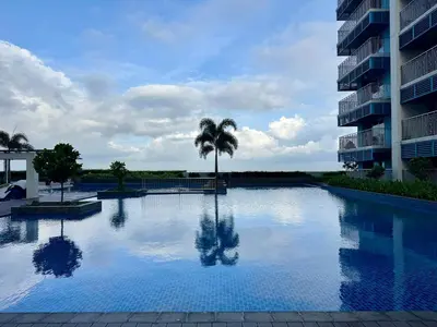 a large swimming pool with a palm tree in front of a building at Panoramic Seaview 2BR near Airport Facing the Bay 6G in Manila
