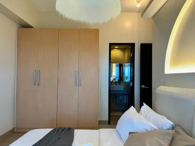 a bedroom with a white bed and a cabinet at Panoramic Seaview 2BR near Airport Facing the Bay 6G in Manila