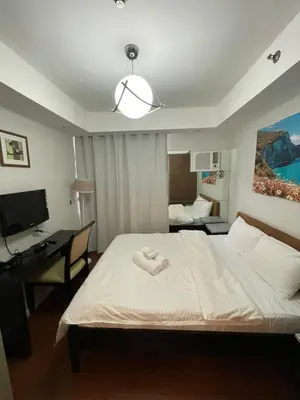a bedroom with a bed with a desk and a computer at Antel Spa Residences 1908 in Manila