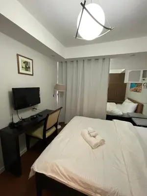 a bedroom with a bed with a desk and a television at Antel Spa Residences 1908 in Manila