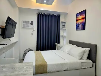 a bedroom with a bed and a television in it at Modern Cozy Studio in Dasmariñas