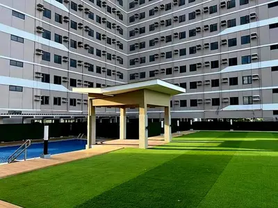 a large building with a green lawn in front of it at Modern Cozy Studio in Dasmariñas