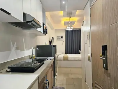 a kitchen with a sink and a room with a bed at Modern Cozy Studio in Dasmariñas