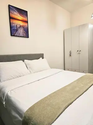 a bedroom with a white bed with a picture on the wall at Modern Cozy Studio in Dasmariñas