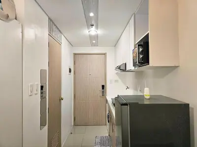 a kitchen with a refrigerator and a door to a hallway at Modern Cozy Studio in Dasmariñas