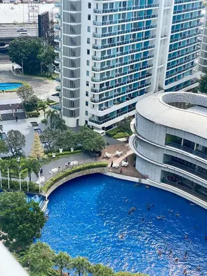 a large pool in front of a building with tall buildings at Azure Daily in Manila