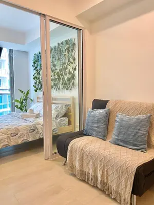 a bedroom with a bed and a couch and a mirror at Azure Daily in Manila