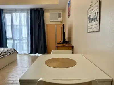 a living room with a table and chairs and a bed at Naia T3 Condotel in Manila