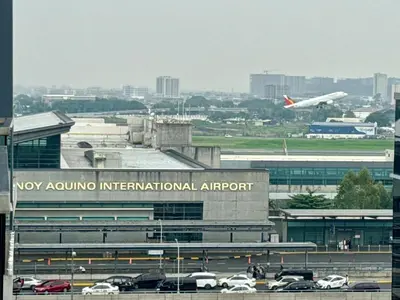 an airport with an airplane taking off in the distance at Naia T3 Condotel in Manila