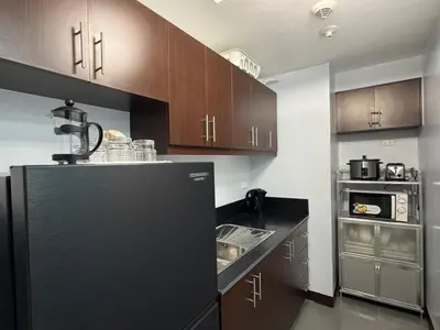 a kitchen with brown cabinets and a black refrigerator at Newport City Home- Naia T3 in Manila