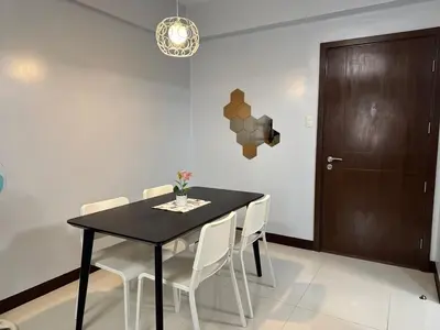 a dining room with a black table and white chairs at Newport City Home- Naia T3 in Manila