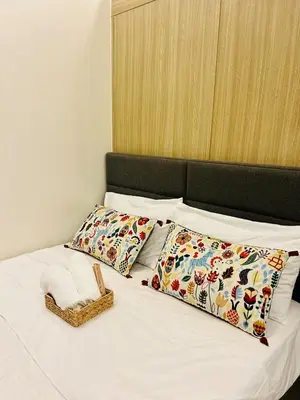 a bed with two pillows and a basket on it at 7 Mins from MOA Comfy Stay with Pool View and WiFi in Manila