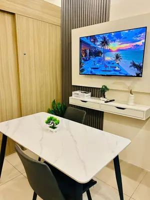 a white table with chairs and a tv on a wall at 7 Mins from MOA Comfy Stay with Pool View and WiFi in Manila