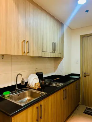 a kitchen with a sink and wooden cabinets at 7 Mins from MOA Comfy Stay with Pool View and WiFi in Manila
