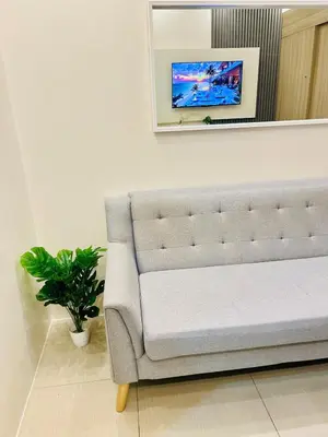 a white couch in a room with a tv on the wall at 7 Mins from MOA Comfy Stay with Pool View and WiFi in Manila