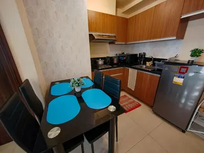 a kitchen with a table with blue chairs and a refrigerator at Manila Bay View - 1BR with balcony in Manila