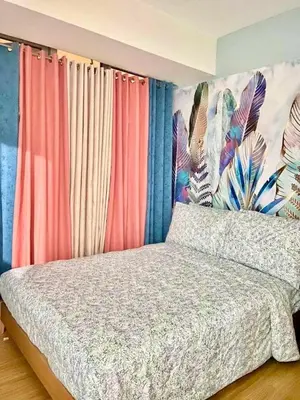 a bedroom with a bed with colorful curtains at Leisure escape Azure staycation in Manila