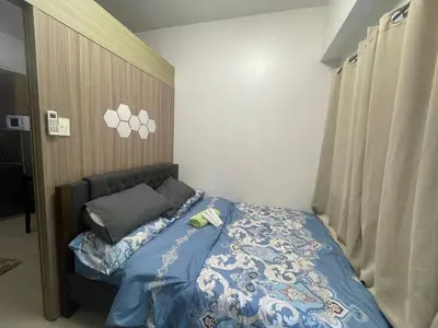 a bedroom with a bed with a blue comforter at Lynx staycation in Manila
