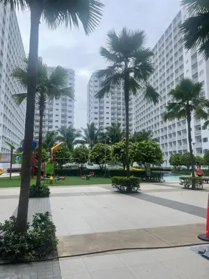 a park with palm trees in front of tall buildings at Lynx staycation in Manila