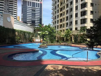 a large swimming pool in a city with tall buildings at Rustic 1 BR Apartment Poolside View in Manila