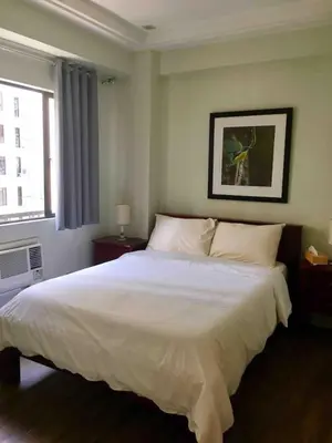 a bedroom with a large white bed with a window at Rustic 1 BR Apartment Poolside View in Manila