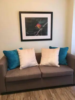 a couch with pillows and a picture of a bird at Rustic 1 BR Apartment Poolside View in Manila