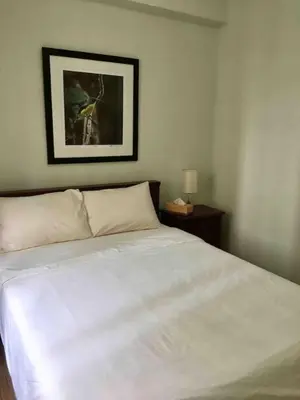 a bedroom with a white bed and a picture on the wall at Rustic 1 BR Apartment Poolside View in Manila