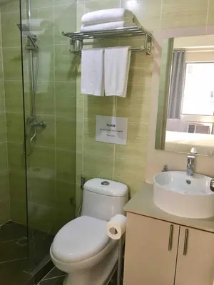 a bathroom with a toilet and a sink and a shower at Rustic 1 BR Apartment Poolside View in Manila