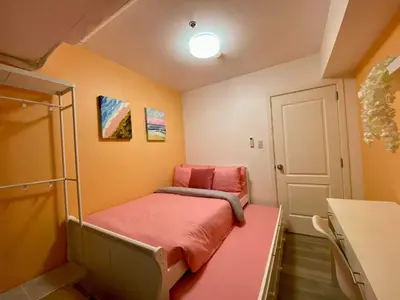 a small room with a bed with a pink blanket at Leisure escape Azure in Manila