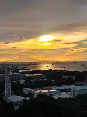 a sunset over a city and the water with boats at Seaside Sanctuary and Beach Vibes in Manila