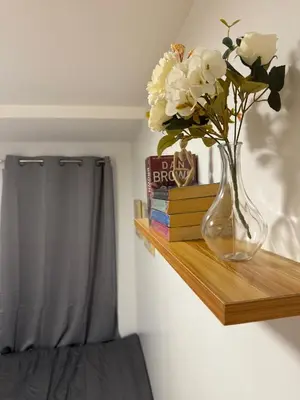 a vase with white flowers on a wooden shelf at BnJ Suite Urban Deca w Netflix, Max, YT Premium, FREE parking in Manila