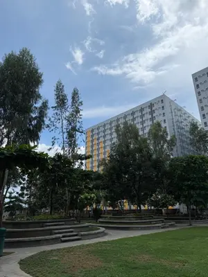 a park with trees and a building in the background at BnJ Suite Urban Deca w Netflix, Max, YT Premium, FREE parking in Manila
