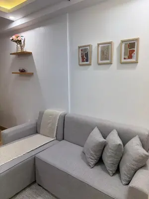 a gray couch in a living room with some pillows at BnJ Suite Urban Deca w Netflix, Max, YT Premium, FREE parking in Manila