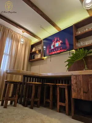 a bar with wooden stools and a tv on the wall at El Nissi Staycation, THE DELUXE CABIN, Enchanted Kingdom in Santa Rosa