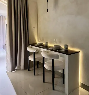 a dining room table with two stools and a table and chairs at Stylish 1BR with balcony inside BGC at Uptown Parksuites - 20d in Manila