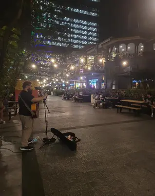 a man playing a guitar on a stage at night at Stylish 1BR with balcony inside BGC at Uptown Parksuites - 20d in Manila
