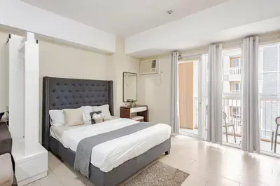 a bedroom with a large bed and a balcony at Classy Venice Grand Studio Balcony Pet friendly, WiFi & Pool in Manila