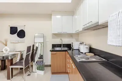 a kitchen with white cabinets and a black counter top at Classy Venice Grand Studio Balcony Pet friendly, WiFi & Pool in Manila