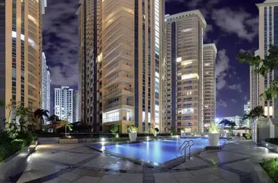 a pool in the middle of a city at night at Classy Venice Grand Studio Balcony Pet friendly, WiFi & Pool in Manila