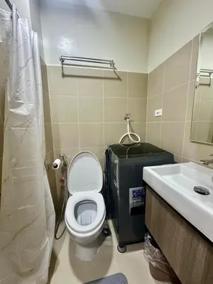 a bathroom with a toilet and a sink at Mall of Asia Staycation with fast wifi and google tv in Manila