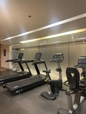 a gym with several treadmills and a mirror at Mall of Asia Staycation with fast wifi and google tv in Manila