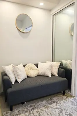 a couch with pillows sitting in a room with a mirror at NEMM Staycation in Manila