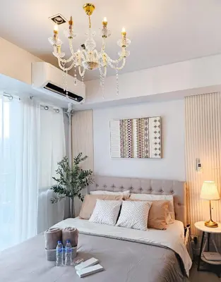 a bedroom with a large bed and a chandelier at NEMM Staycation in Manila