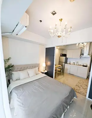 a bedroom with a large bed and a chandelier at NEMM Staycation in Manila