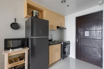 a kitchen with a stainless steel refrigerator and wooden cabinets at 2 BR Golf View Loft Timeless Charm in Avant BGC in Manila