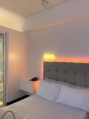 a bedroom with a bed with a love sign on the wall at Staycation by Darvy in Manila