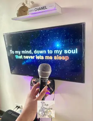 a person holding a microphone in front of a tv at Staycation by Darvy in Manila